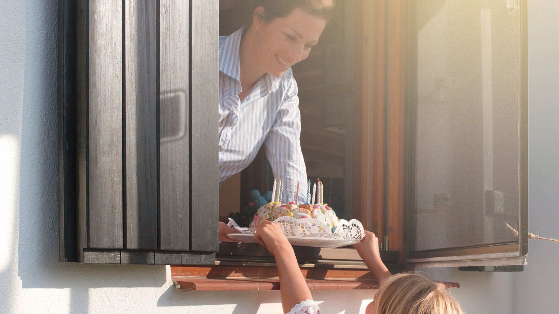 Frau überreicht Kinde Kuchen durch Pendelfenster