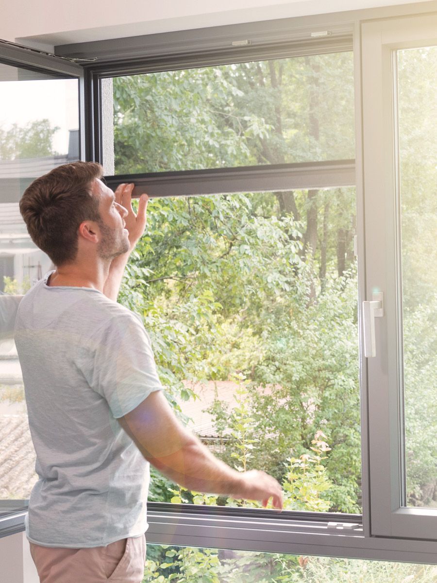 Mann bedient Insektenschutzrollo