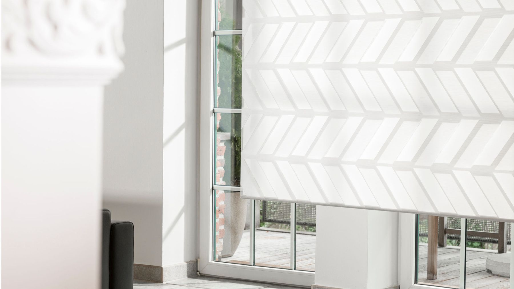 Weißes gemustertes Rollo in einem bodentiefen Fenster